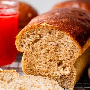 rye bead with a slice cut off with red jam in the background.