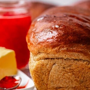 loaf of rye bread on a cooling rack with butter and jam.