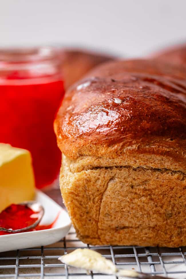 loaf of rye bread on a cooling rack with butter and jam.