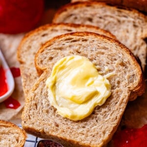 butter on a slice of rye bread with a spoonful of jam on the side.