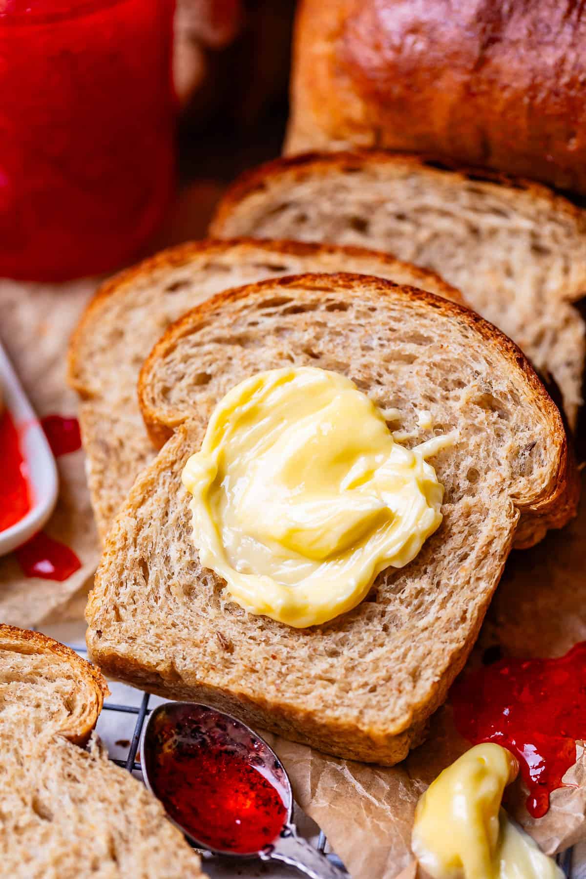 butter on a slice of rye bread with a spoonful of jam on the side.