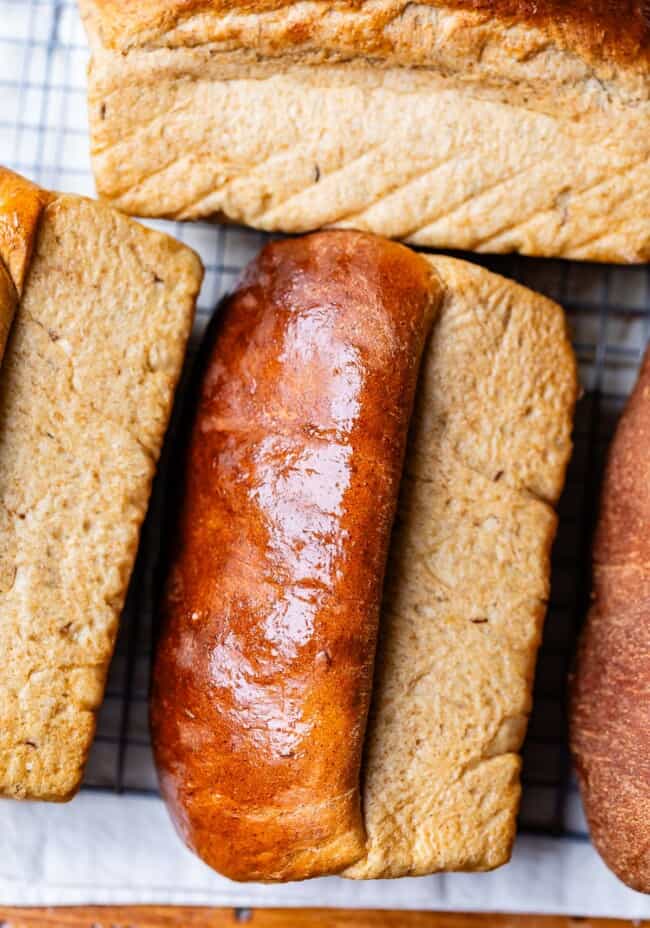 several loaves of bread lying on their sides to let cool with smooshing the bottom.