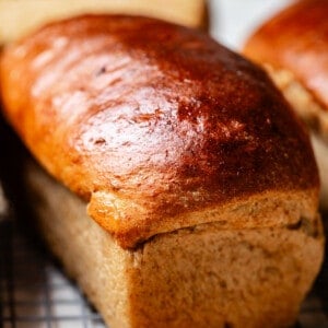 side shot of a loaf of rye bread on a cooling rack.
