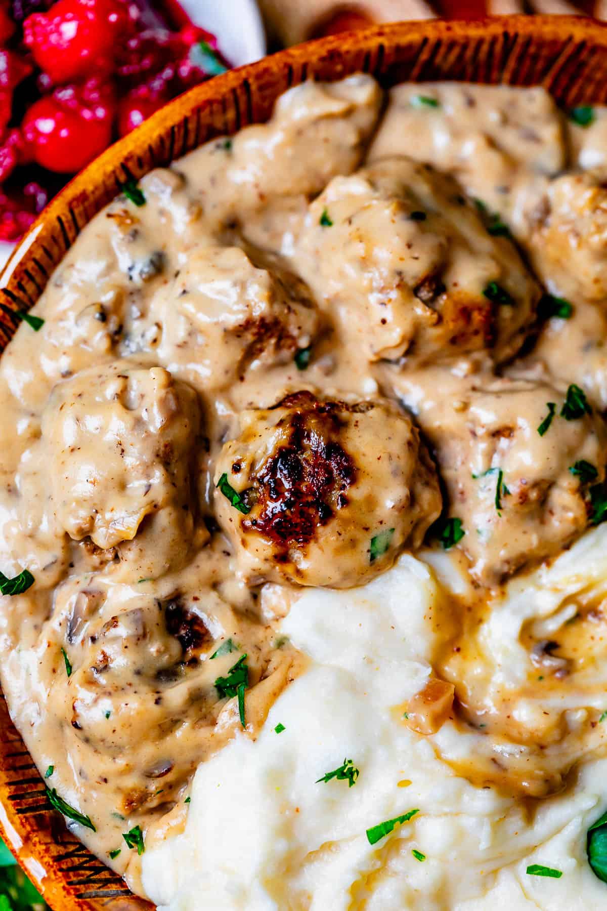 swedish meatballs in creamy gravy poured over the top of mashed potatoes in a bowl.