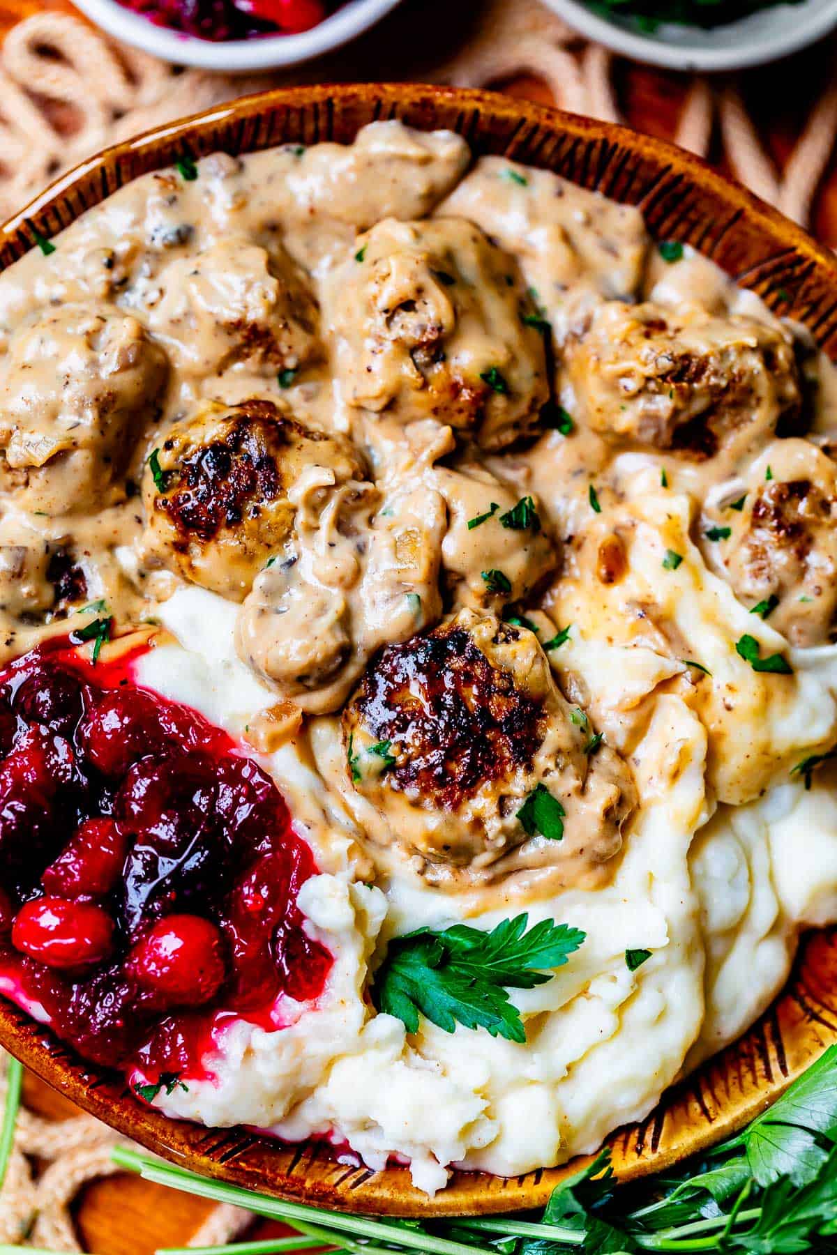a bowl filled with mashed potatoes, swedish meatballs in sauce, and cranberry sauce.