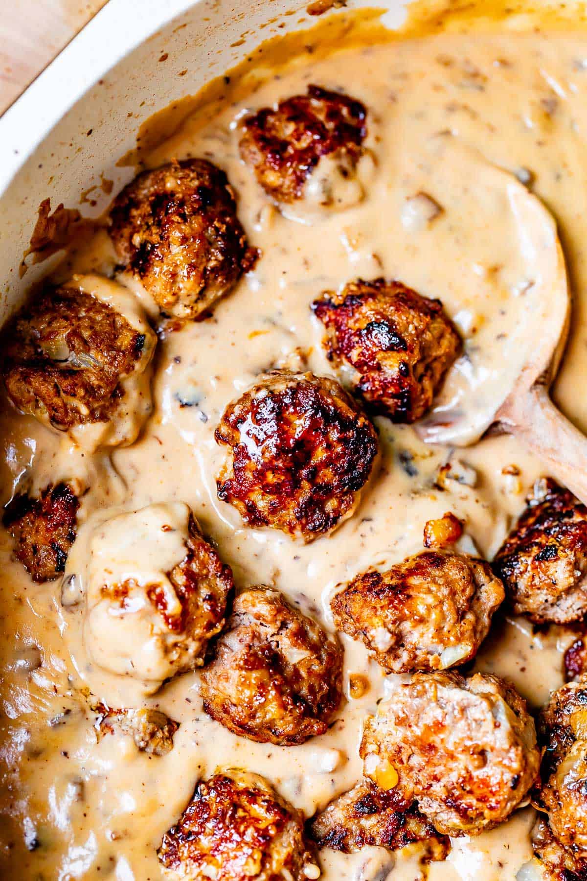 looking down into a skillet filled with creamy brown gravy, and swedish meatballs.