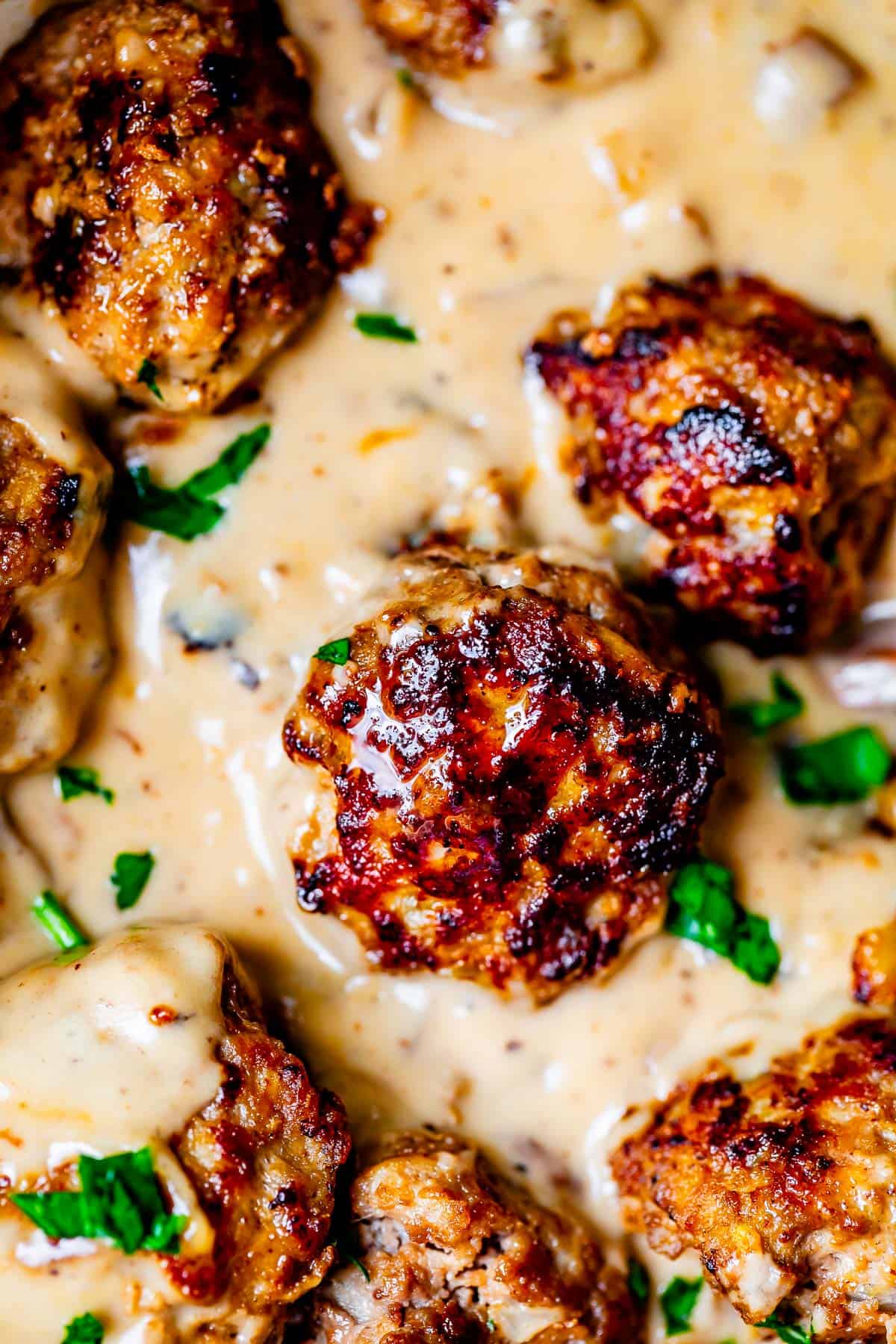 close up of three swedish meatballs nestled in with delicious creamy brown sauce.