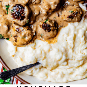 brown meatballs in a gravy sauce with mashed potatoes on a plate.