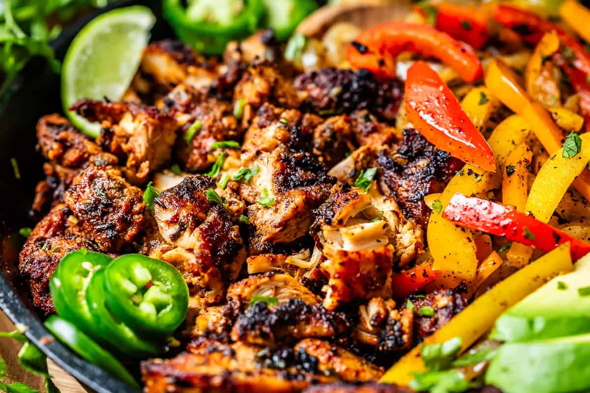 looking closely at charred fajita chicken, with lime and jalapeno slices as garnish.