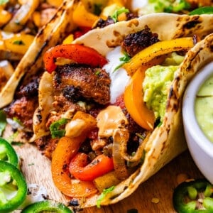 a filled chicken fajita next to a bowl with creamy tomatillo jalapeno sauce for dipping.