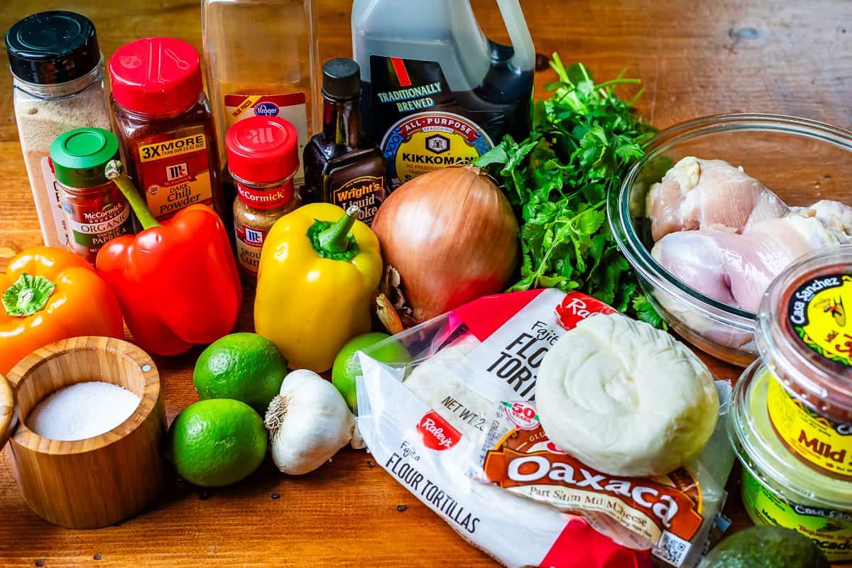 picture of ingredients for chicken fajitas like tortillas, chicken, peppers, onions, etc.