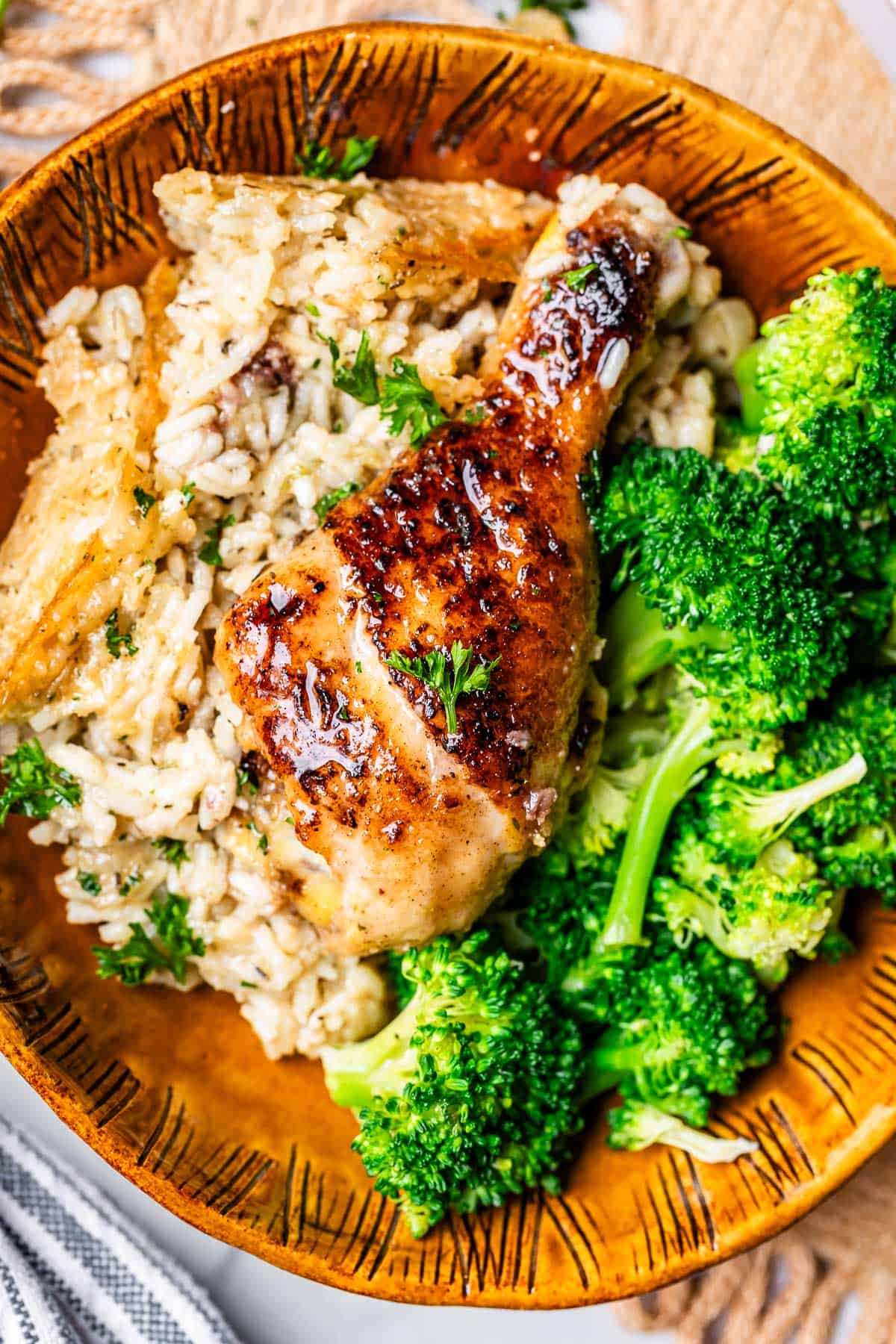 creamy rice, cooked chicken drumstick, and broccoli in a ceramic bowl.