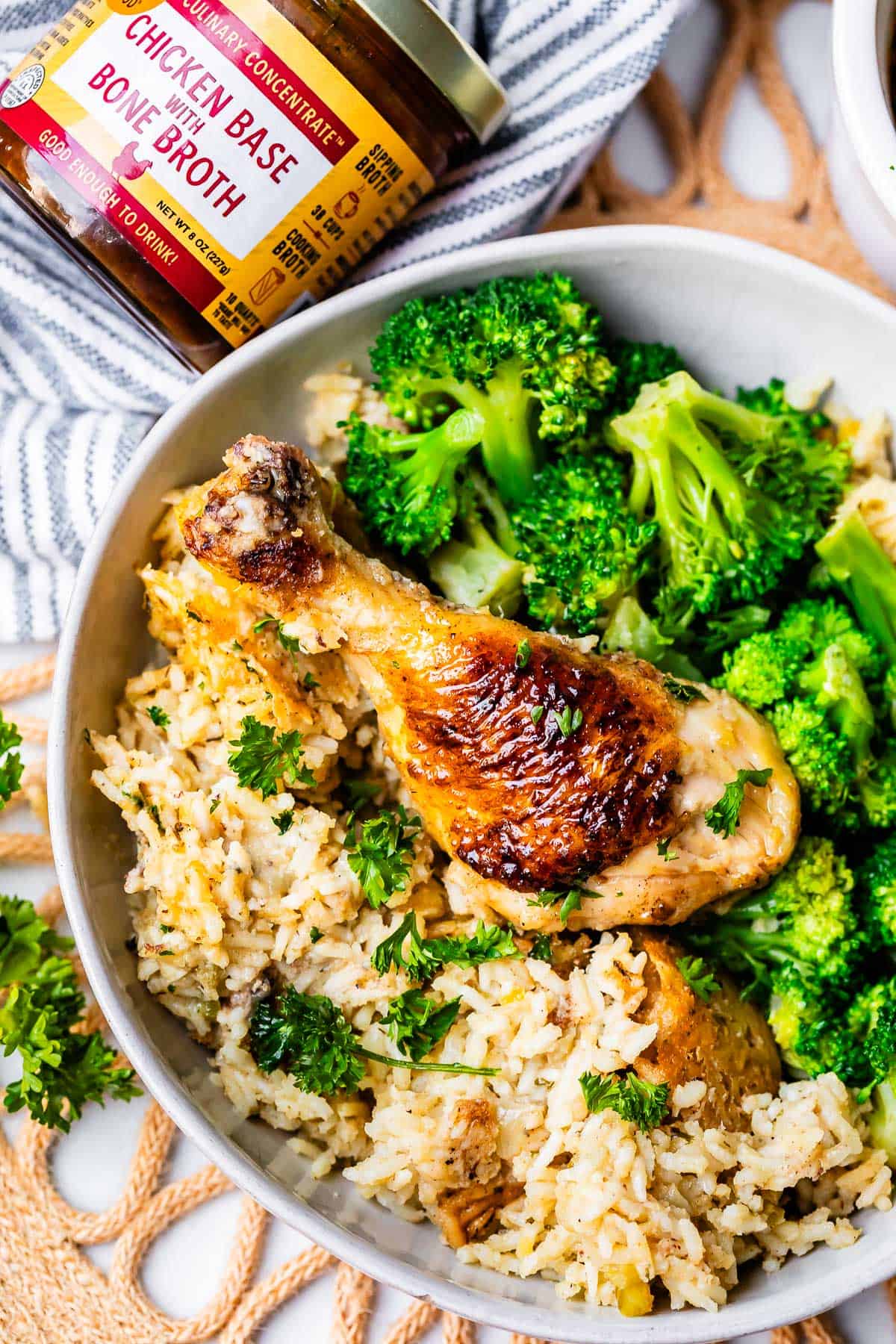 browned chicken drumstick with rice from the casserole and broccoli in a ceramic bowl.