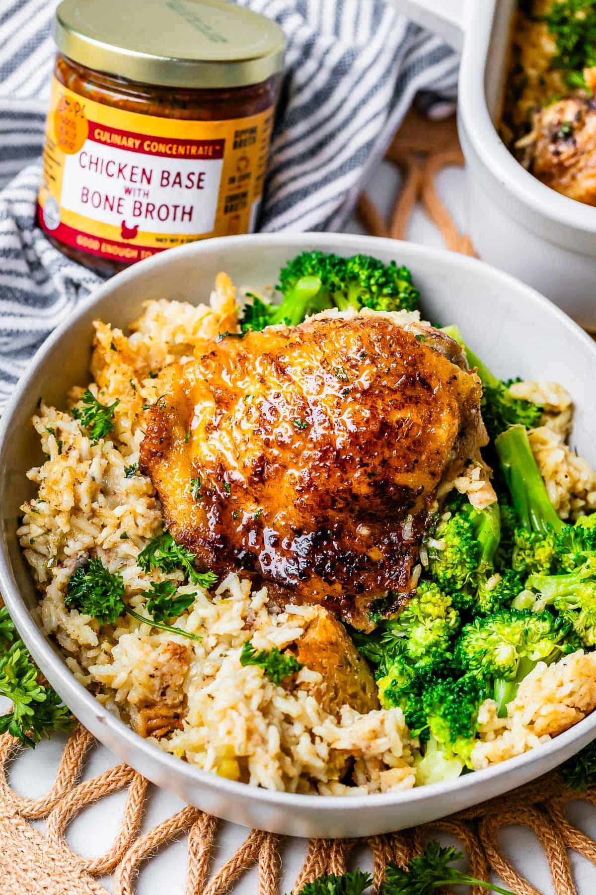well seared chicken thigh on a bed of creamy rice with broccoli in a bowl.