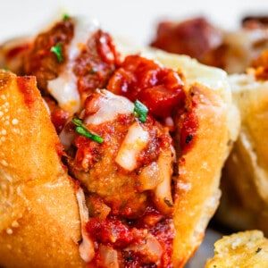 sideways view looking into the first bite of a meatball sub with all the sauce and cheese.