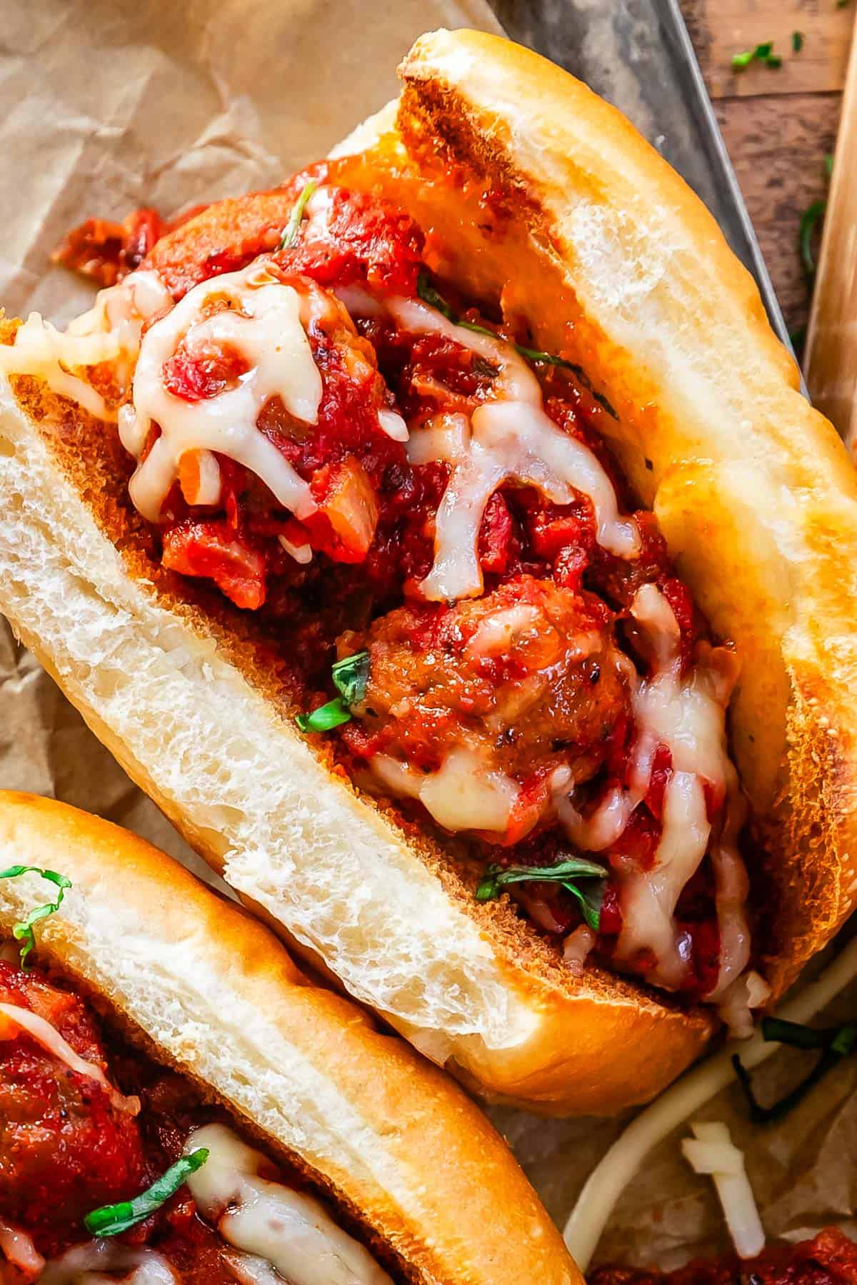 close up shot of a meatball sub with toasty buns, meatballs and sauce, and melty cheese.