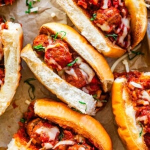 ready to serve meatball sandwiches with melty cheese on parchment paper.