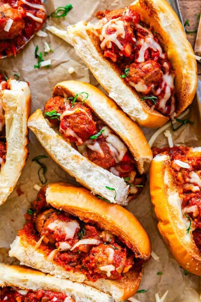 ready to serve meatball sandwiches with melty cheese on parchment paper.