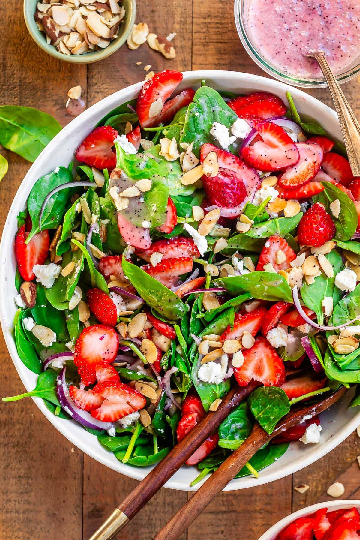 dressed strawberry spinach salad with poppyseed dressing ready to serve with tongs.