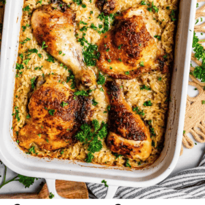 overhead shot of browned chicken thighs and drumsticks and rice in a white casserole dish.
