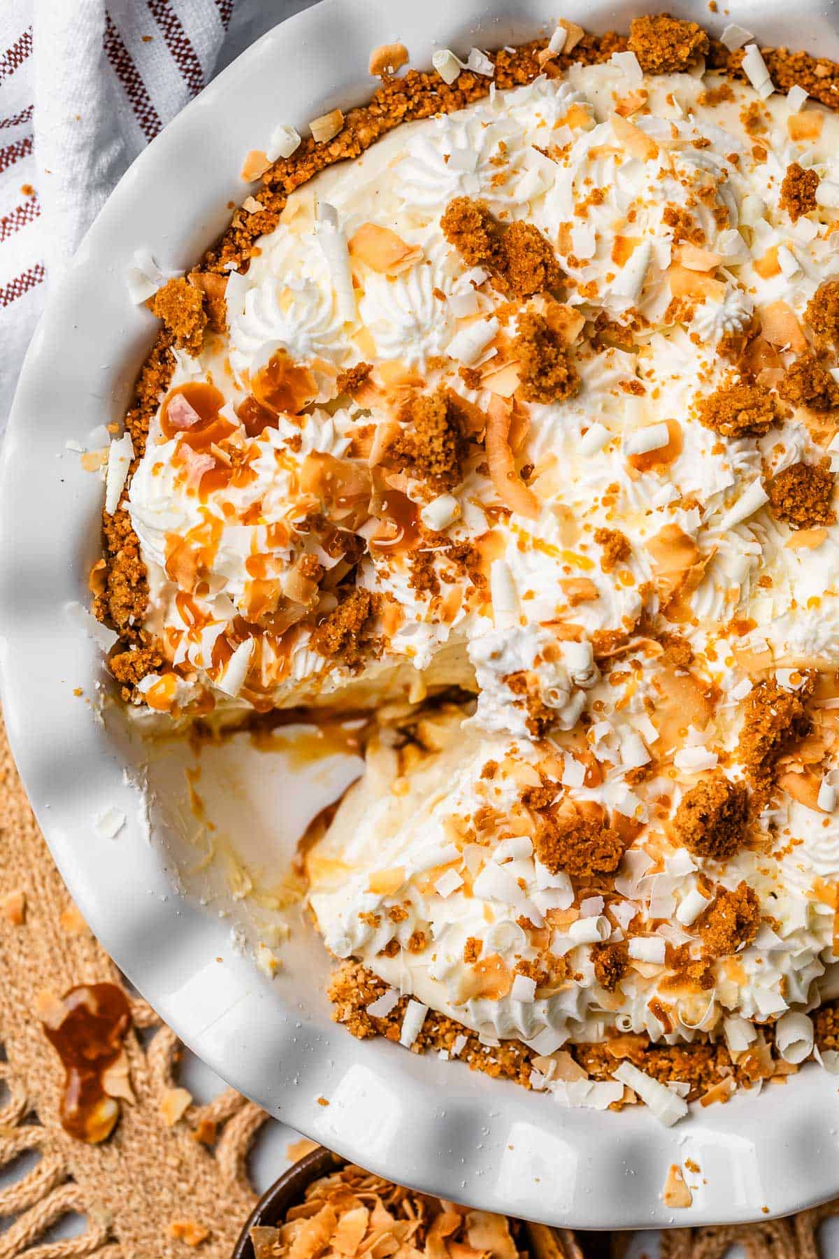 overhead shot of coconut cream pie in a white dish with whipped cream topping.