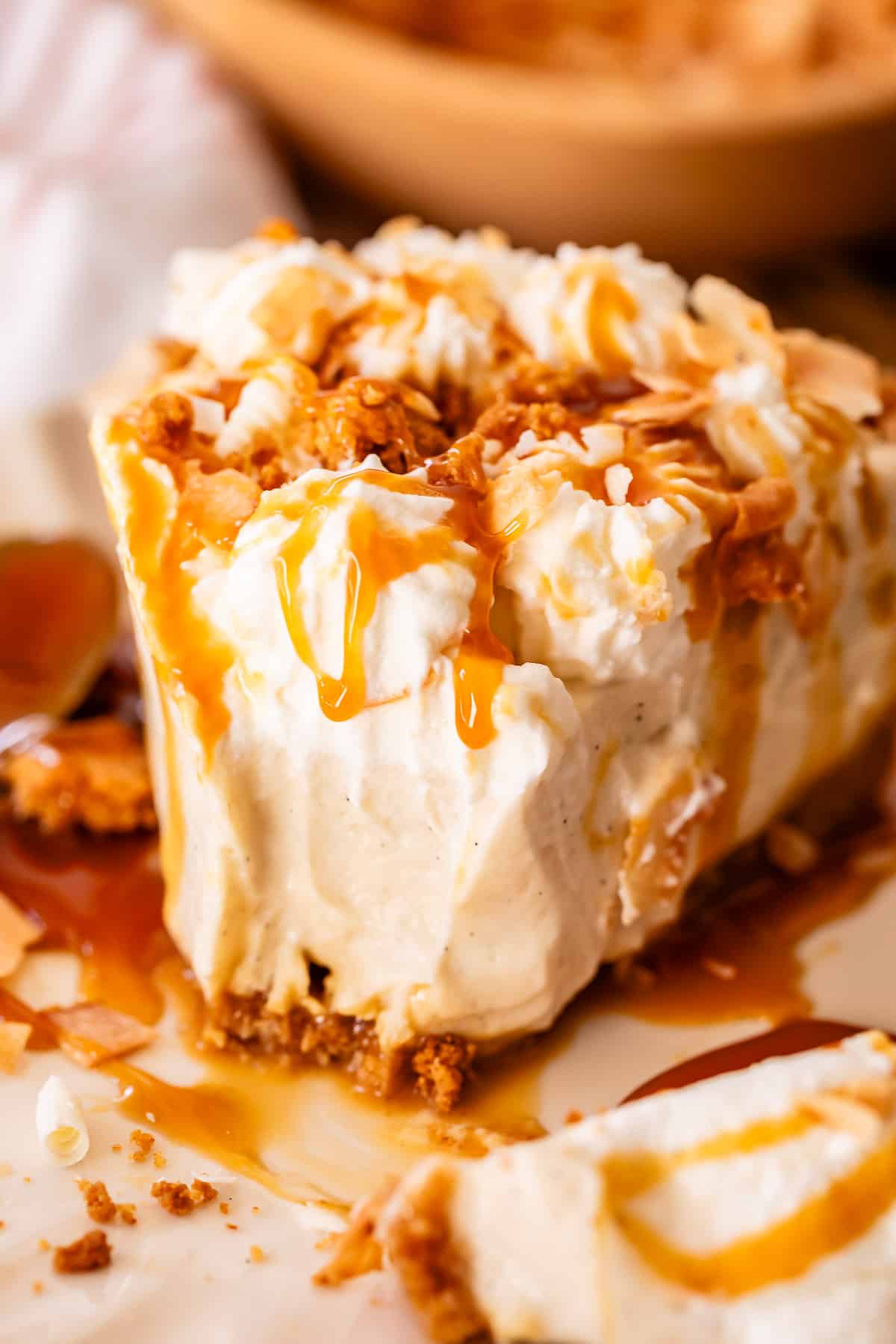 half eaten slice of coconut cream pie on a white plate with caramel drizzle.