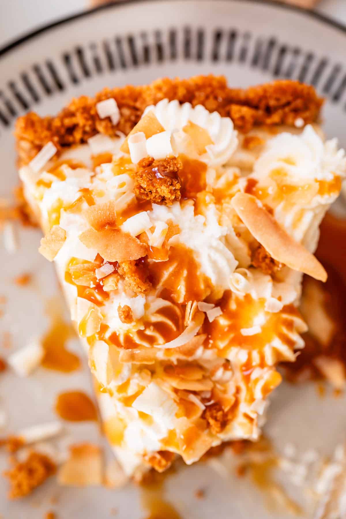 overhead shot of a slice of coconut cream pie with toasted coconut and caramel drizzle.