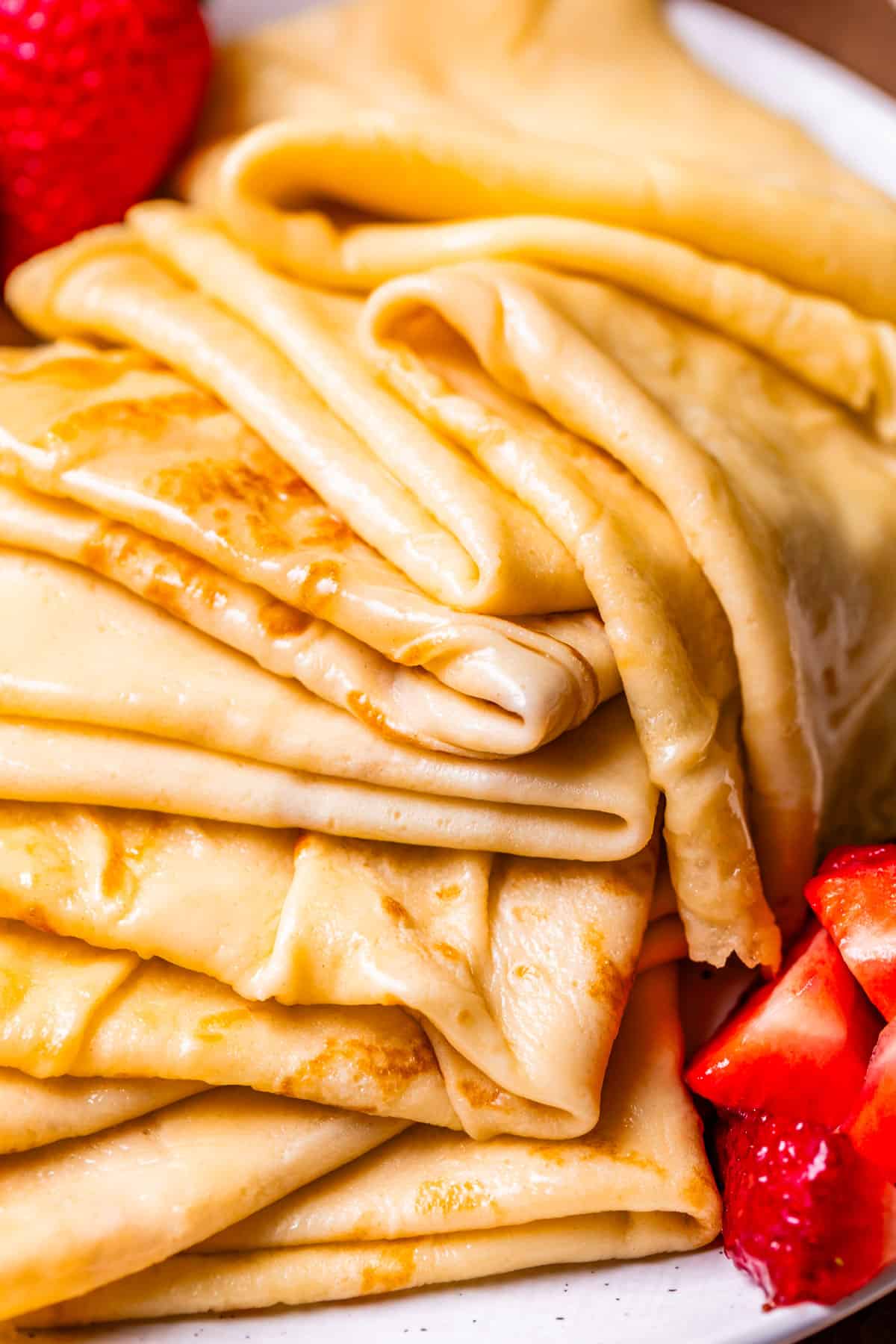 huge stack of quarter folded crepes with strawberries on the side.