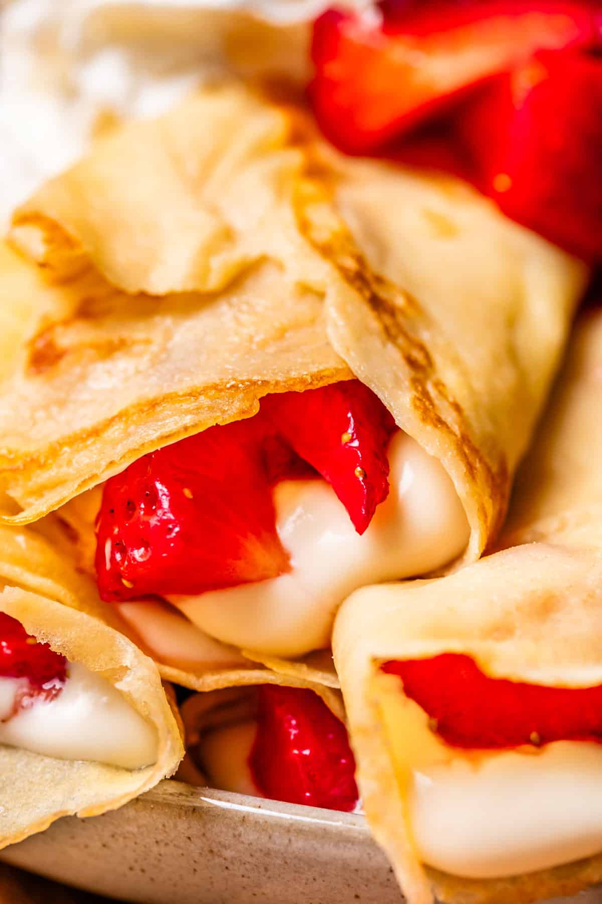 close up of a crepe stuffed with cream cheese spread and strawberry topping.
