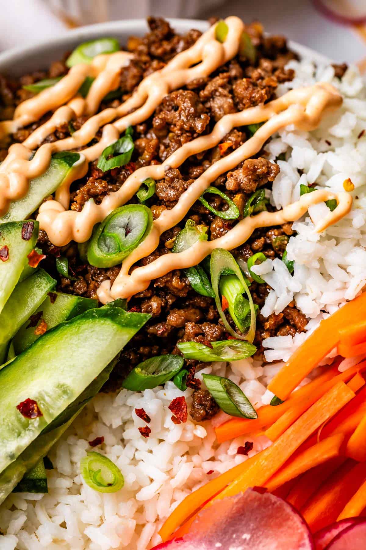 close up of rice topped with Korean beef and drizzled with Sriracha mayo.