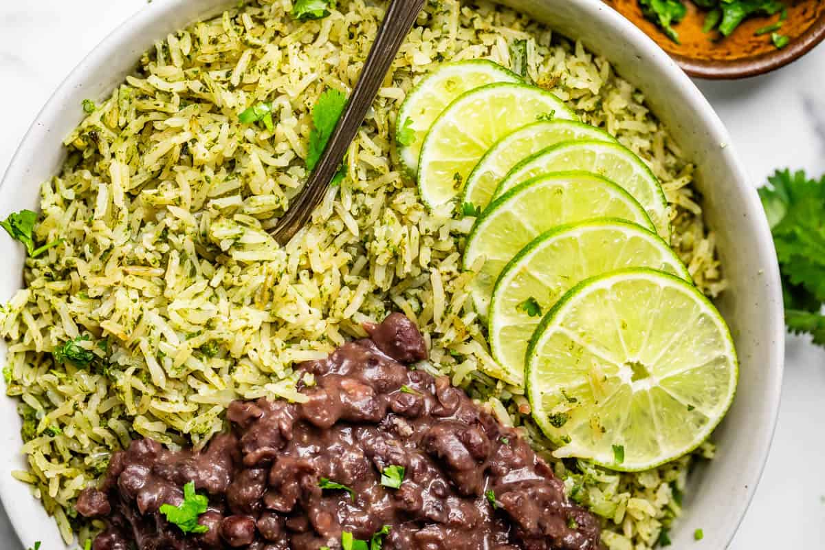 large bowl with cilantro lime rice and quick black beans, with a spoon and lime slices.