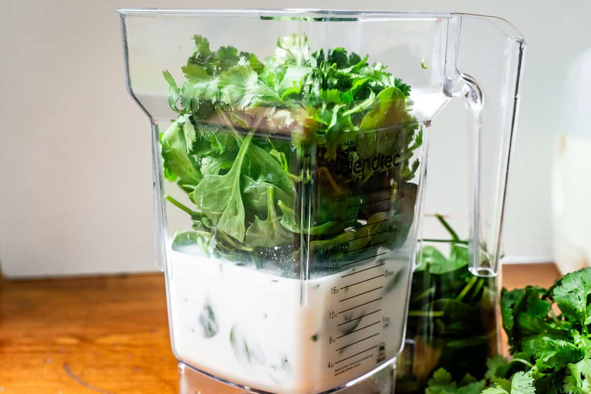 a blender filled with milk, broth, spinach, and cilantro for cilantro lime rice.