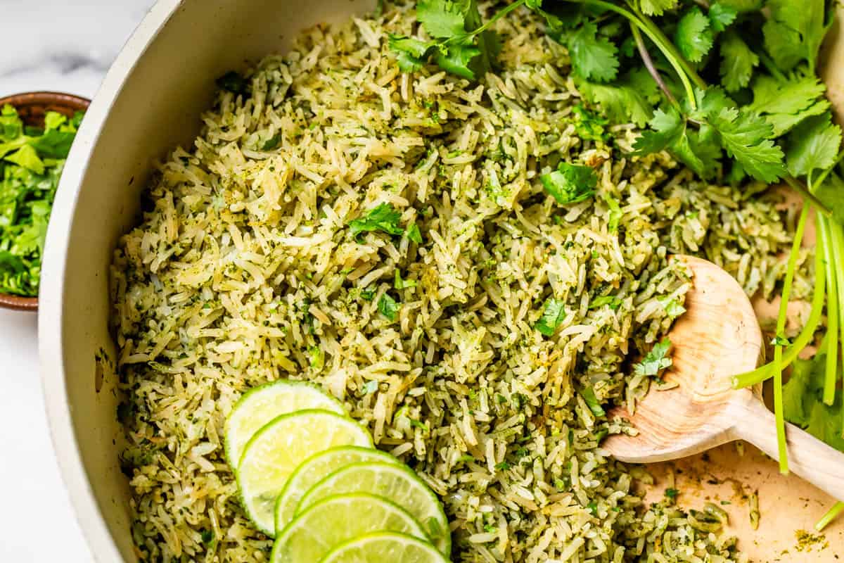 a large wooden serving spoon stirring a pot of cooked cilantro lime rice.