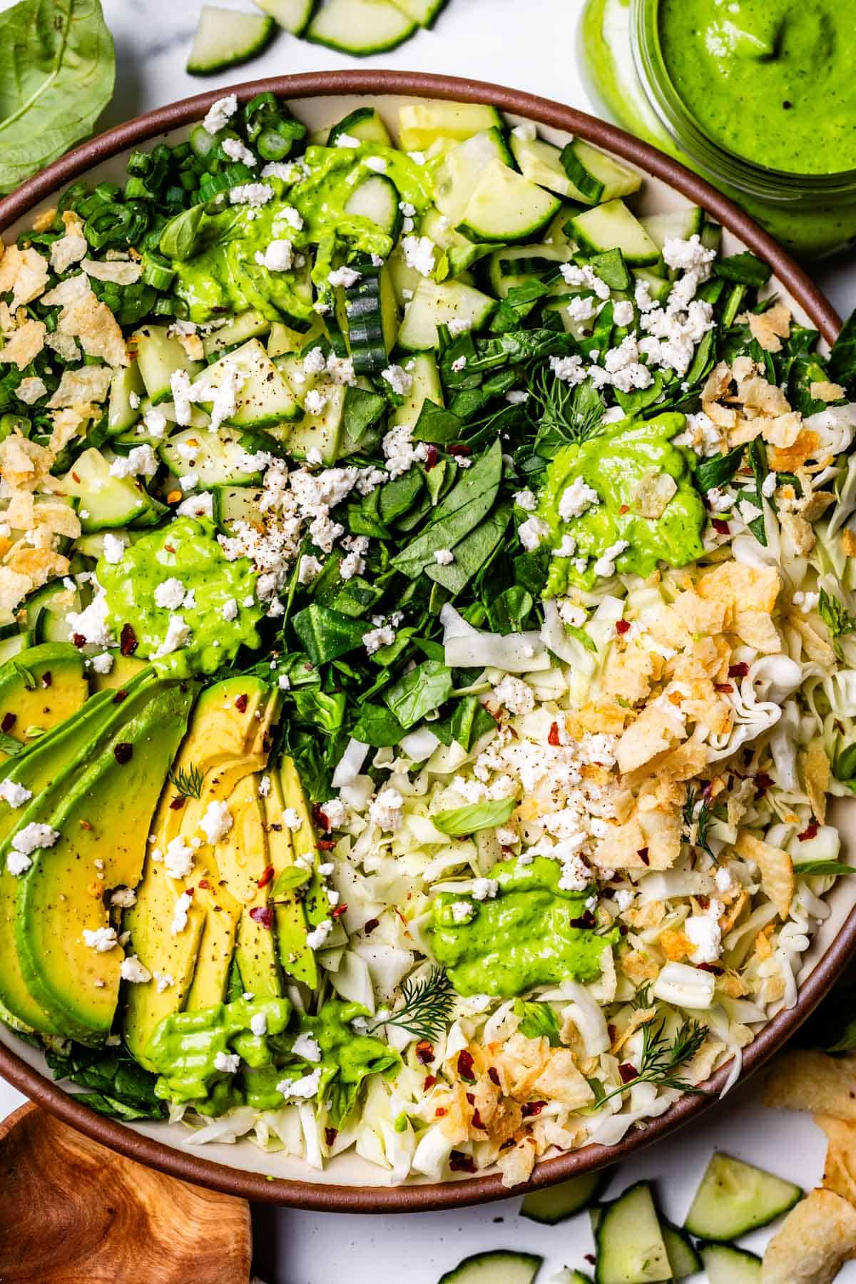 plate of green goddess salad topped with avocado and feta cheese.