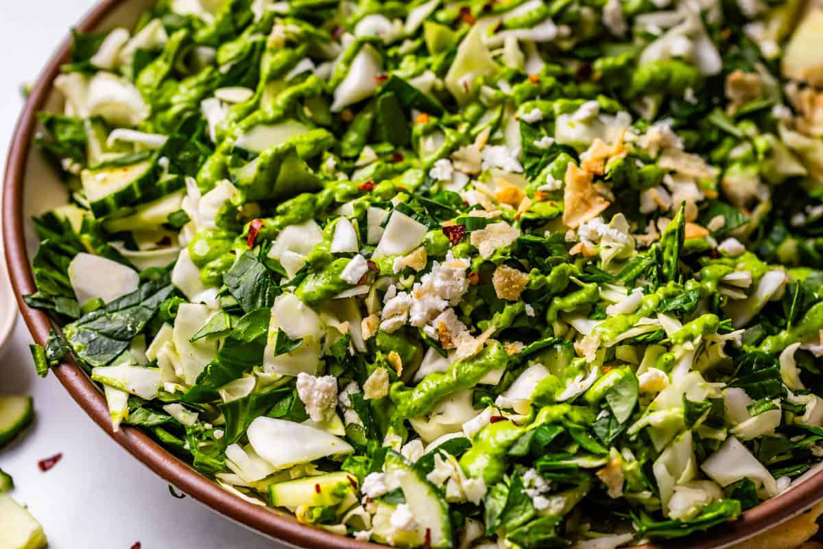 close up of green goddess salad on a plate and topped with dressing and salt & vinegar chips.