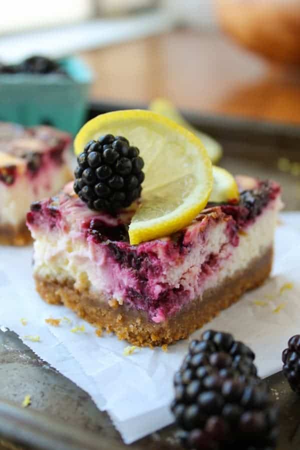 a thick crust blackberry lemon cheesecake bar on parchment paper. 