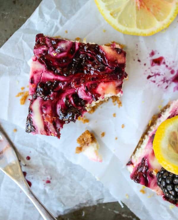 a blackberry lemon cheesecake bar with a bite taken out of it. 