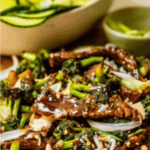 A bowl of beef and broccoli stir-fry served over white rice, garnished with sauce and fresh vegetables, with a side of cucumber salad in the background. Text above reads Make Your Own Beef and Broccoli – Skip the Takeout.