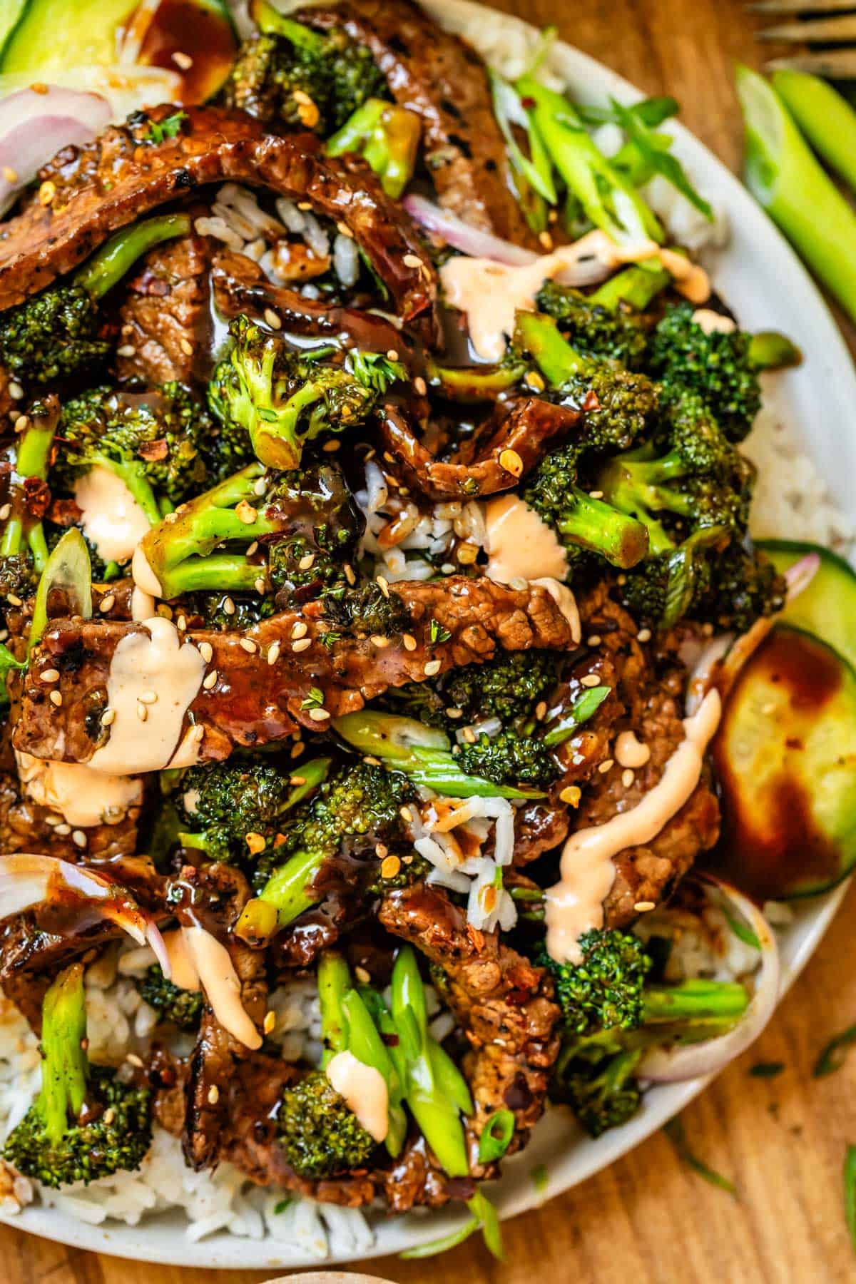 plate of beef strips with sauce and broccoli and cucumbers.