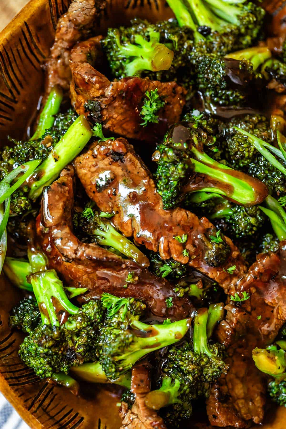 beef and broccoli stir fry in an orange clay bowl.