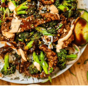 overhead shot of white plate with strips of beef and broccoli florets with cucumber garnish.