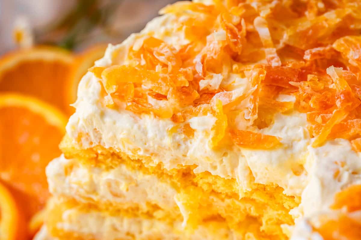 close up of layered pig pickin cake with thinly chopped dried mandarin oranges on top.