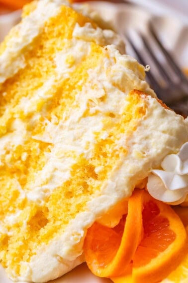 slice of four layers of yellow mandarin cake layered with pineapple whipped cream on a plate.