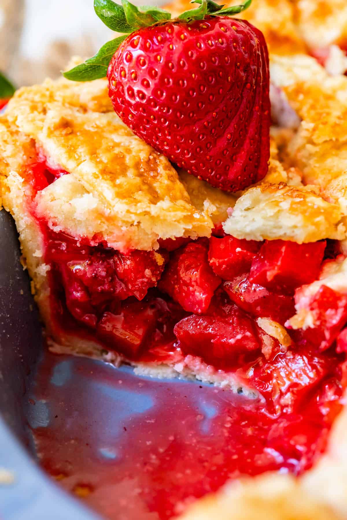 looking at the side of a piece of pie with all the strawberry and rhubarb filling showing.