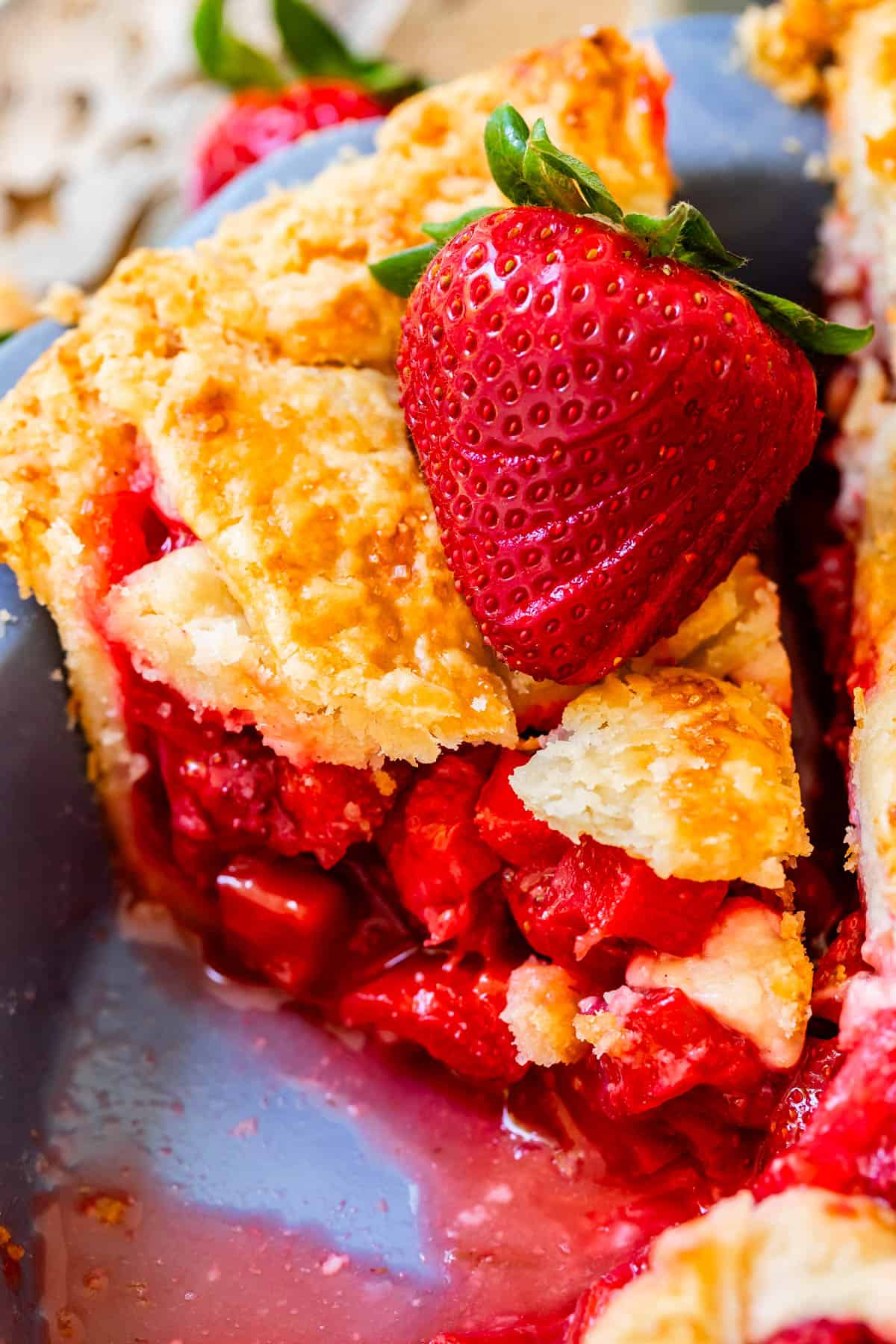 piece of lattice crust strawberry and rhubarb pie with lots of filling and fresh strawberry garnish.