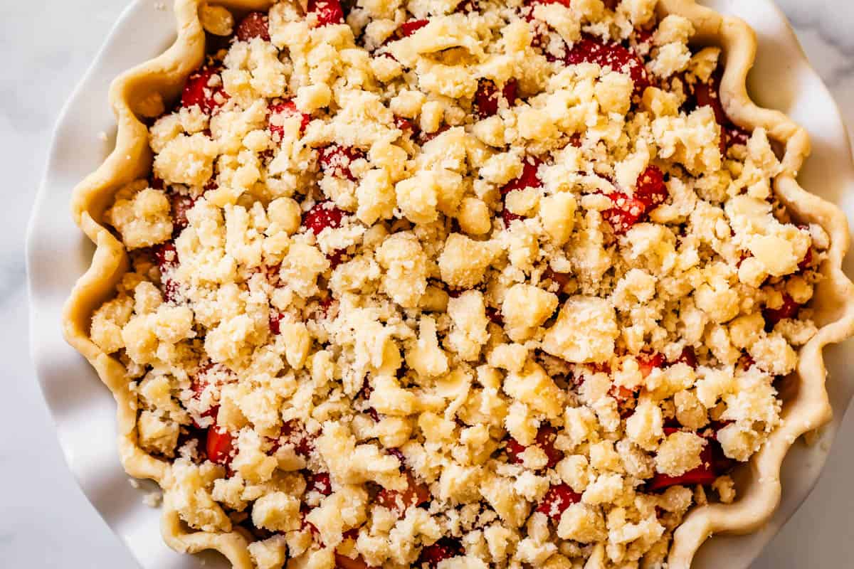 looking down at a strawberry rhubarb pie with crumble on top ready to bake.