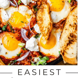 A skillet filled with shakshuka—eggs poached in tomato sauce—topped with cheese, green onions, and served with toasted bread. Text reads: Easiest Shakshuka Recipe You’ll Ever Make. The Food Charlatan.