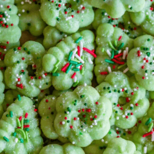A pile of green holiday spritz cookies decorated with red, white, and green sprinkles, perfect for a spritz cookie recipe.