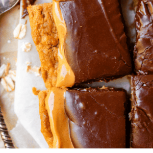 Close-up of chocolate-topped peanut butter bars, sliced into rectangles, with creamy peanut butter layers visible. Text over the image reads “Slap Yo Mama Lunch Lady Peanut Butter Bars - The Food Charlatan dessert.”.