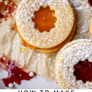 round butter cookie with a cutout of orange apricot jam with powdered sugar.